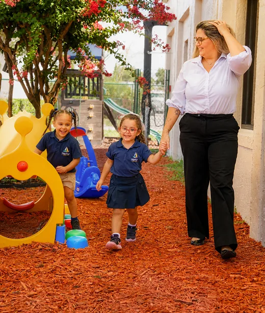 Teacher walking hand in hand with two children in the Harbor playground