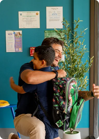 Teacher greeting a child with a hug at drop-off